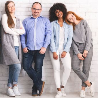 Four smiling adults of diverse backgrounds standing side-by-side against a wall