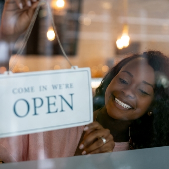 Woman placing an open sign on a business window