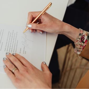 Woman with polished nails signing a contract with gold pen