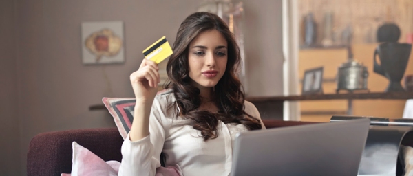 Young woman holding credit card looking at a laptop. 