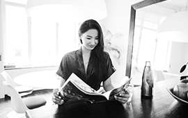 Black and white photograph of a woman reading a magazine