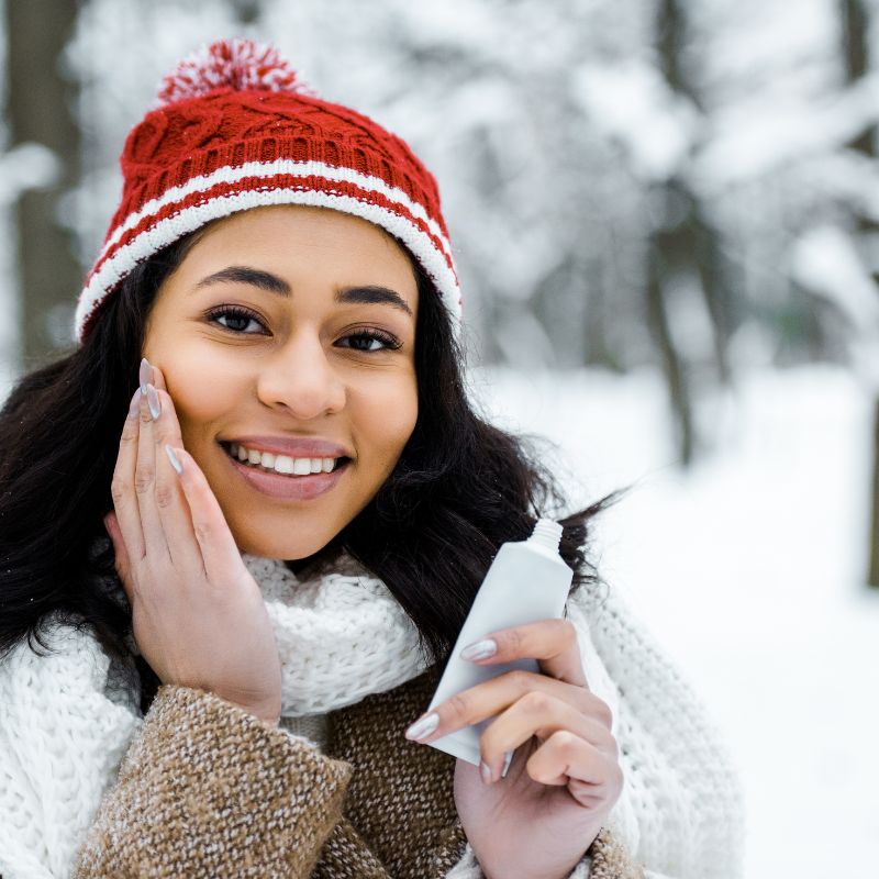 woman applying cream in winter forest