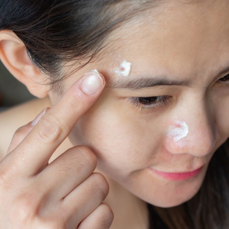 Image of a person using face cream above their eyes.