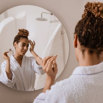 Image of a person doing their makeup in the mirror.