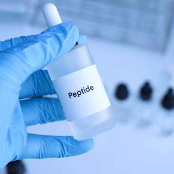 Image of medical gloves holding a bottle of peptides.