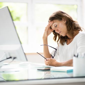 person sitting at a desk looking stressed.