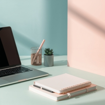 Open laptop on desk with two notebooks and pen