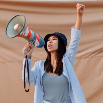 Woman holding a megaphone raising her hand in a fist in a call for advocacy