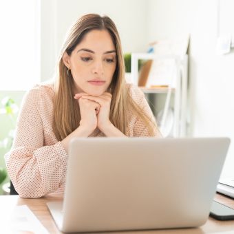 Woman in pink blouse looking at laptop screen