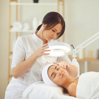 Esthetician adjusting lamp over a client's face