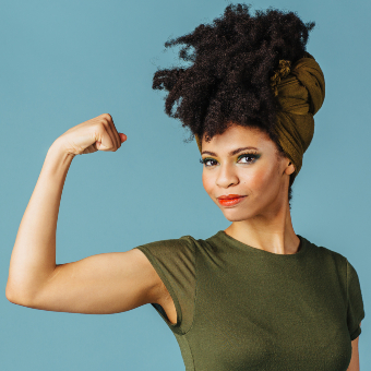 Woman in green shirt with a determined facial expression and showing off her arm muscles