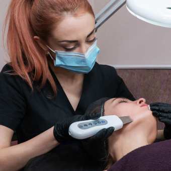 A skincare professional providing a dermatology procedure to a client while wearing ppe.