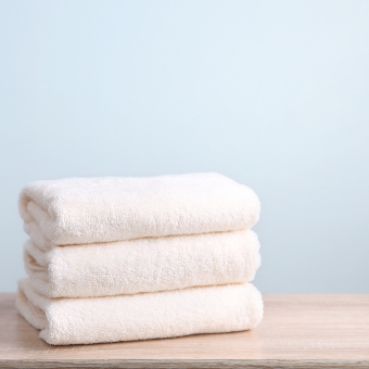 Stack of three clean towels on wooden table. 