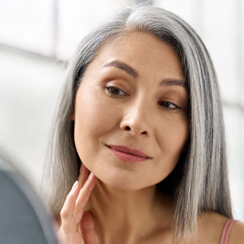 woman looking at her face in the mirror