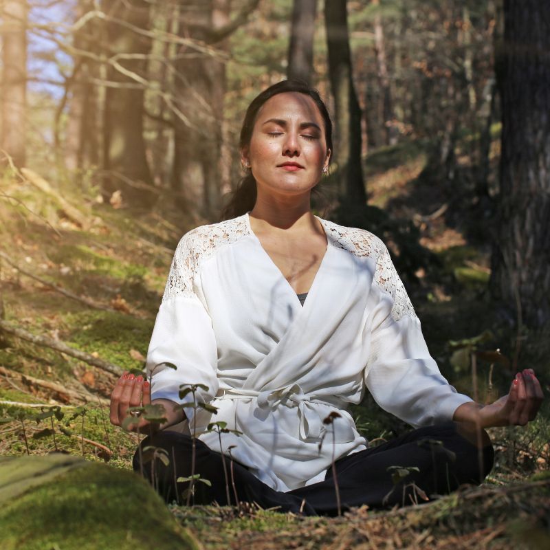 Image of a person meditating in the forest.