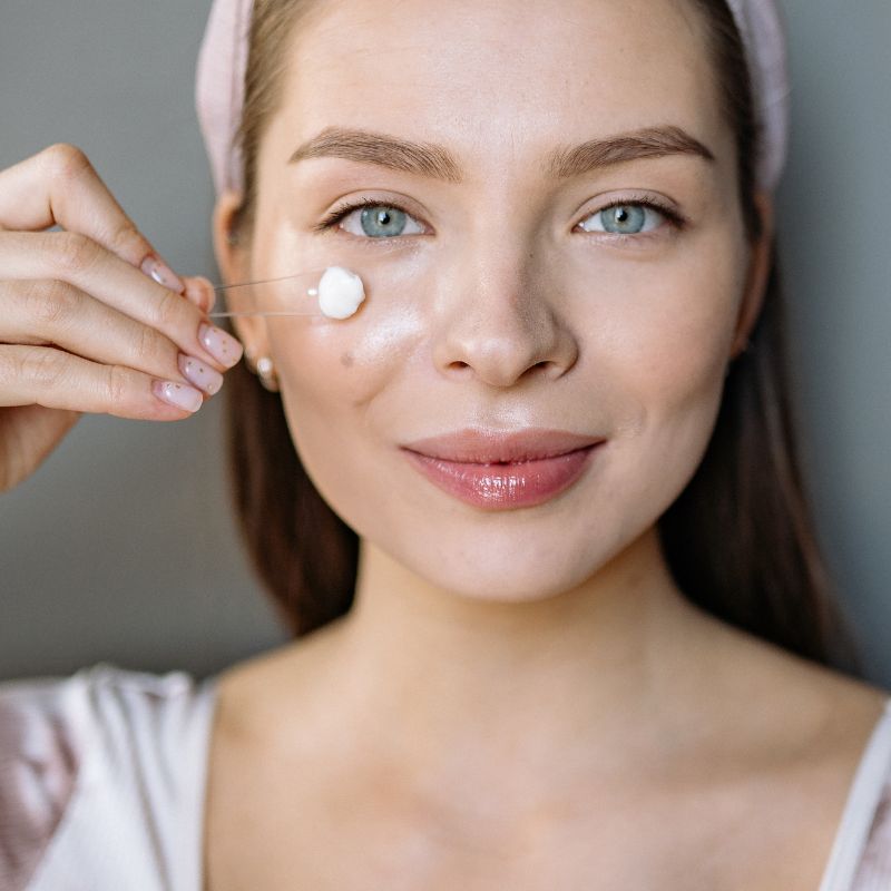 Image of a person applying cream under their eyes.