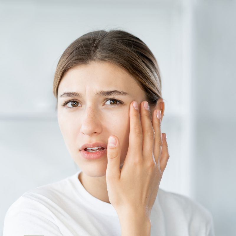 Image of a person looking distressed with their hand to their face.