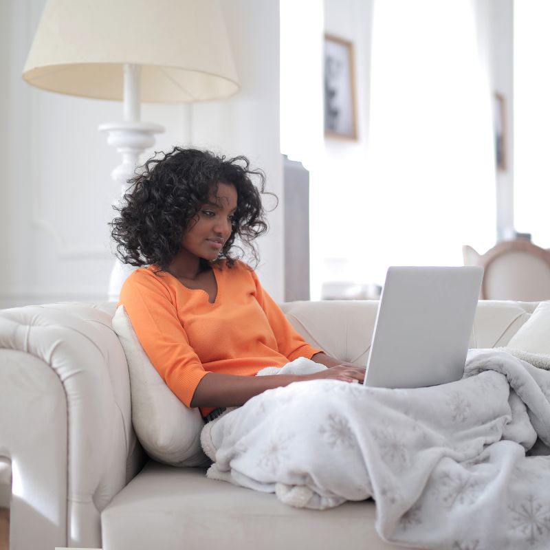 Image of a person sitting on their couch with a laptop.