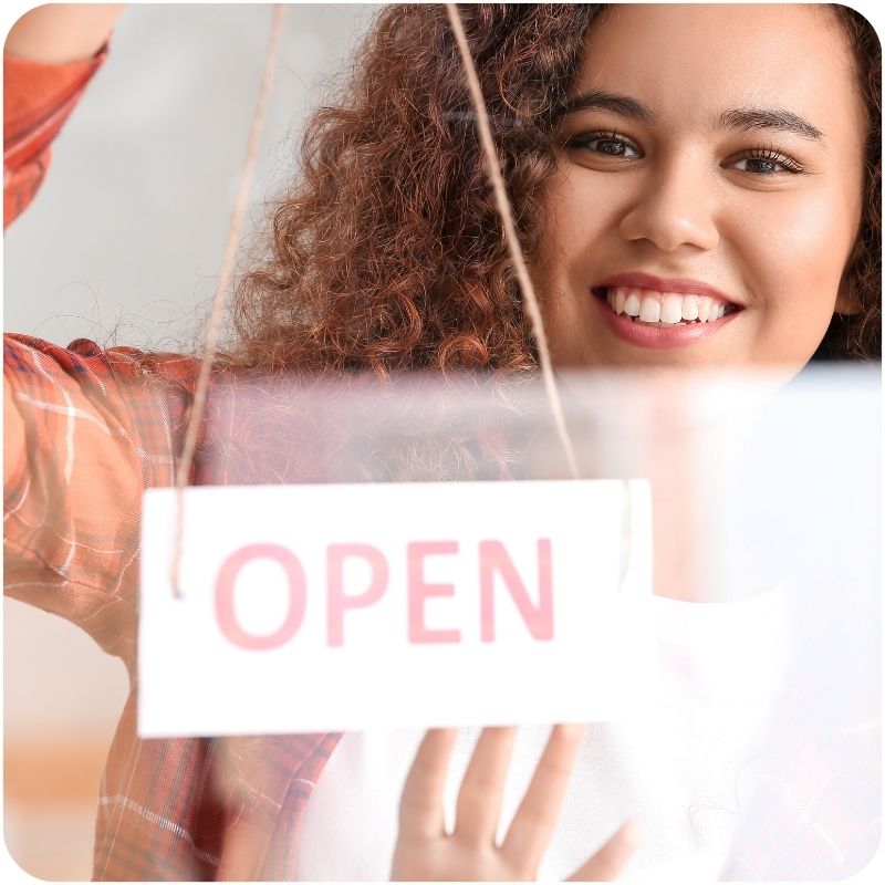 Image of a person hanging an open sign.