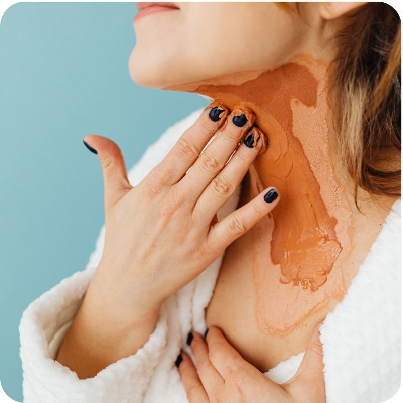 A person applying a moisturizer on her neck.