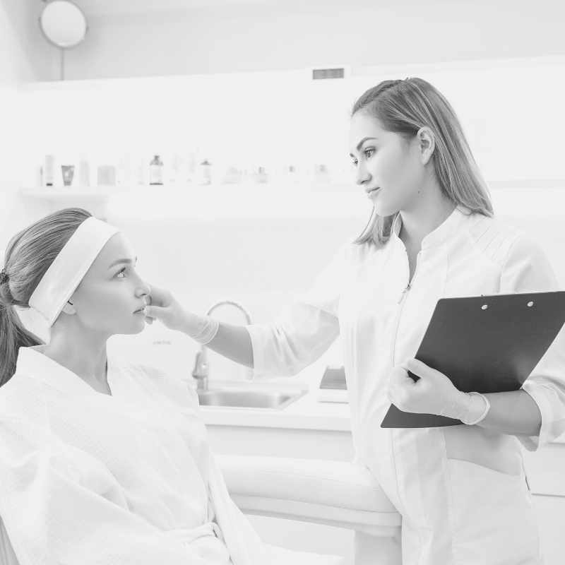 Esthetician holding a clipboard and consulting with client