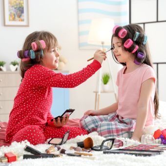 Image of two young children doing each others makeup.