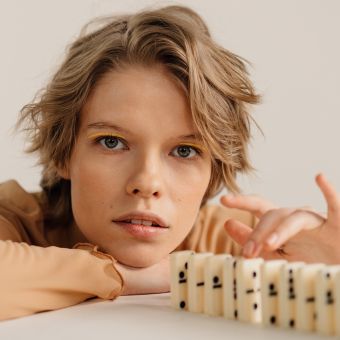 Image of a person behind dominos on a table.