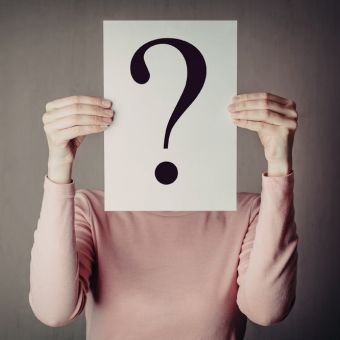 Image of a person holding a sign with a question mark.