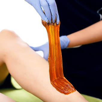 an esthetician preforming sugaring on a client
