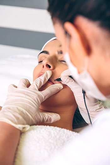 An esthetician performs a radio frequency facial treatment for their client. 