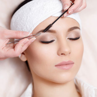 A client receiving an eyebrow procedure from an esthetician using techniques learned at ASCP.