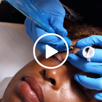 Esthetician performing microblading — Microblading eyebrows with play button overlay 