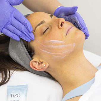Esthetician applying sunscreen to client's skin after a chemical peel.