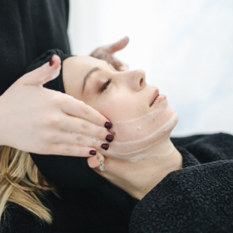 woman with black draping receives a facial